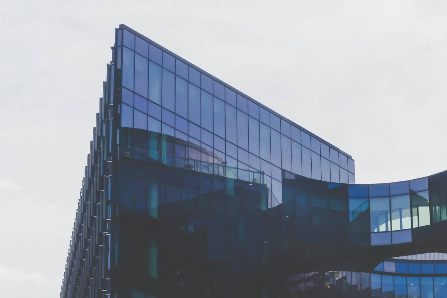 Moderno edificio per uffici in vetro con sezioni angolari e curve.